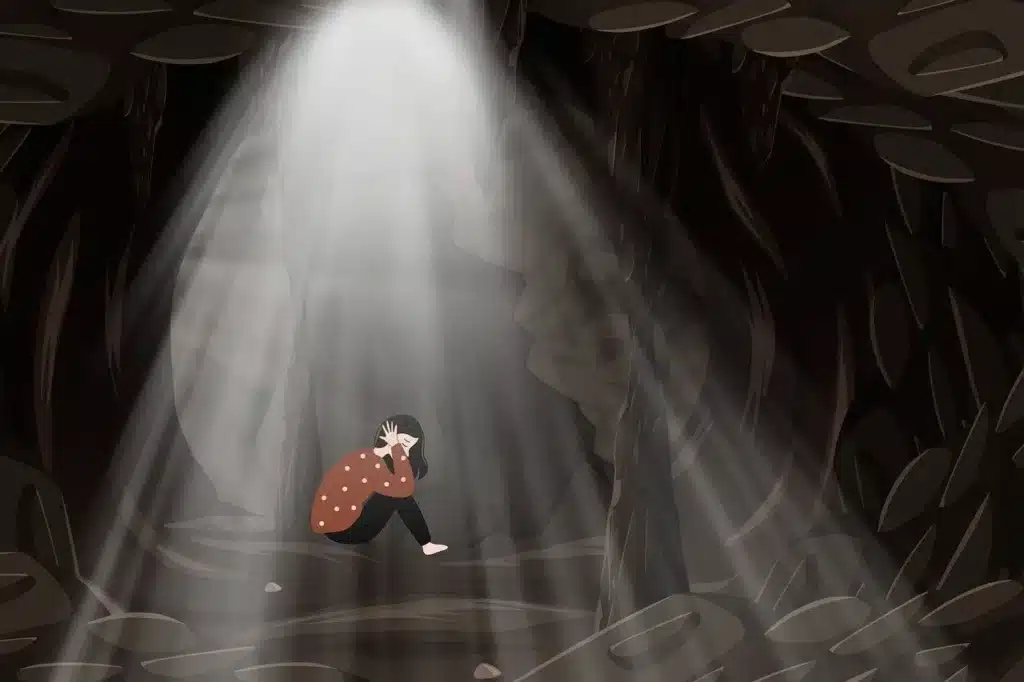 A girl curled up in fetal position inside a dark cave, symbolizing the power of emotions and the importance of support.